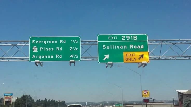 Overhead freeway signage on Interstate 90 in Spokane Valley marking Exit 291B for Sullivan Road, with Evergreen, Pines and Argonne exits signed alongside.